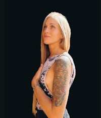 a woman with tattoos on her sleeve posing in front of a black background