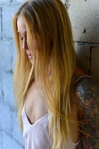 a woman with tattoos leaning against a wall